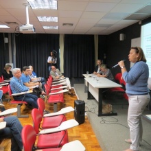 Ao microfone a profa. Denise Fonseca. Na primeira fila o Prof. Hilton Koch, e na mesa a profa. Adriana Geisler. Fotógrafo Antônio Albuquerque. Acervo do Núcleo de Memória.